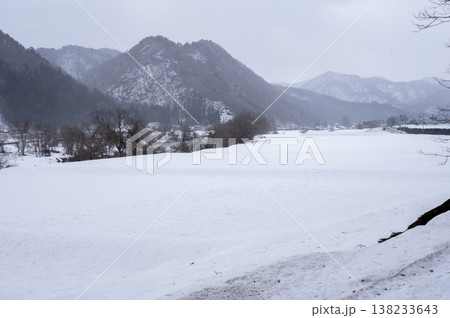 雪降る南会津の冬景色、一面の雪原と雪化粧した山並みが広がる里山の風景 雪降る南会津の冬景色、一面の雪原と雪化粧した山並みが広がる里山の風景 138233643