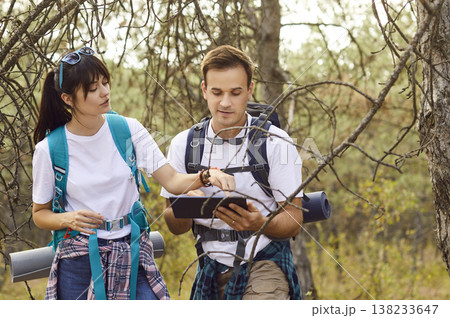 Couple hikers consult digital map on tablet, lost in woods without network Couple hikers consult digital map on tablet, lost in woods without network 138233647