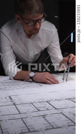 Architect creating technical drawing with compass, designing blueprint on paper for engineering project in office. Concept of architecture and business in low key lighting Architect creating technical drawing with compass, designing blueprint on paper for engineering project in office. Concept of architecture and business in low key lighting 138233691