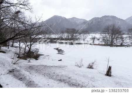 雪降る南会津の冬景色、一面の雪原と雪化粧した山並みが広がる里山の風景 雪降る南会津の冬景色、一面の雪原と雪化粧した山並みが広がる里山の風景 138233703