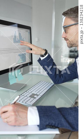 Professional businessman in a blue jacket working on desktop computer in modern office, focusing on his work and business tasks. Business people concept Professional businessman in a blue jacket working on desktop computer in modern office, focusing on his work and business tasks. Business people concept 138234218