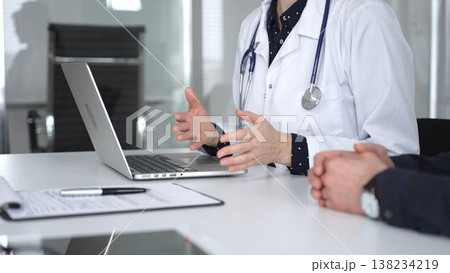 Doctor consulting patient, discussing medical information, using laptop for diagnosis and healthcare data management. Medicine, healthcare and science concept 138234219