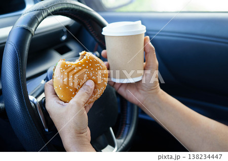 Asian woman driver hold and eat hamburger food in car. 138234447
