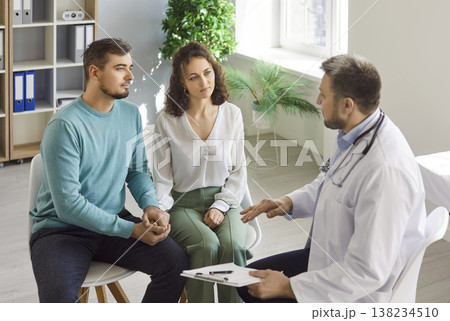 Doctor explaining diagnosis and treatment, health news to couple of patients in hospital office Doctor explaining diagnosis and treatment, health news to couple of patients in hospital office 138234510