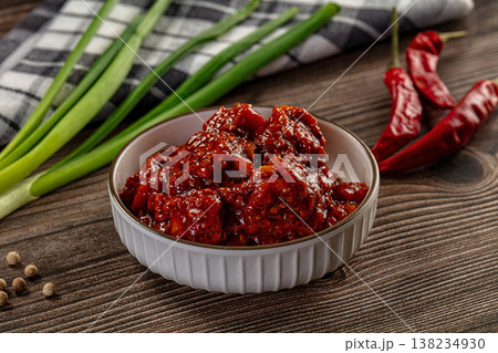Spicy red chili pickle in a white bowl on a rustic wooden table with fresh ingredients Spicy red chili pickle in a white bowl on a rustic wooden table with fresh ingredients 138234930