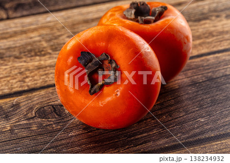 Two ripe orange persimmons on a rustic wooden table 138234932