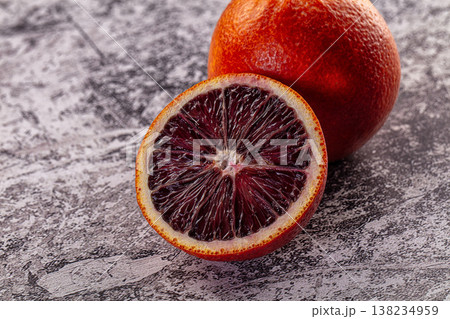 Fresh ripe blood orange, whole and sliced in half on a textured surface. 138234959