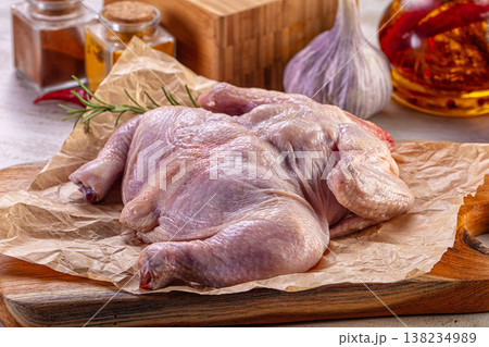 Raw spatchcocked chicken on a wooden cutting board with fresh ingredients for cooking. Raw spatchcocked chicken on a wooden cutting board with fresh ingredients for cooking. 138234989