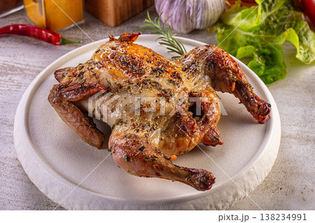 Gourmet roasted quail with herbs on a white plate, surrounded by fresh vegetables and spices. Gourmet roasted quail with herbs on a white plate, surrounded by fresh vegetables and spices. 138234991