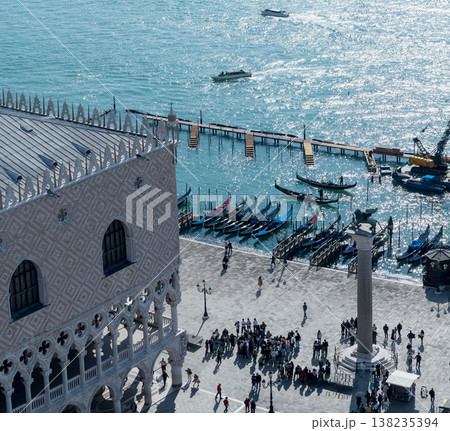 Sunlit Venetian waterfront with gondolas and tourists 138235394