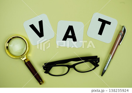 VAT alphabet letters with magnifying glass, eye glasses and pen on yellow background VAT alphabet letters with magnifying glass, eye glasses and pen on yellow background 138235924