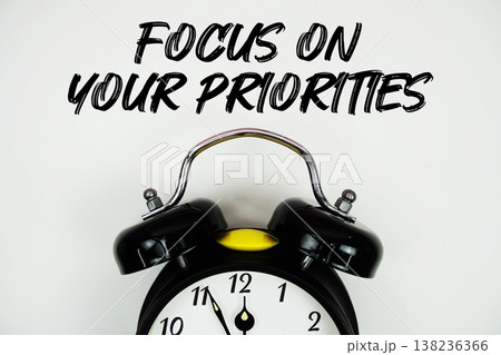 Focus On Your Priorities text with alarm clock flat lay on white background Focus On Your Priorities text with alarm clock flat lay on white background 138236366