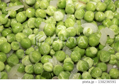 Close up of petit pois peas being fried with chopped garlic in a pan 138236591