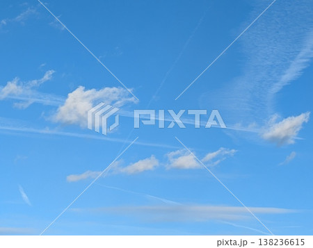 Beautiful blue summer air with fluffy white clouds and chem trail lines across the sky Beautiful blue summer air with fluffy white clouds and chem trail lines across the sky 138236615