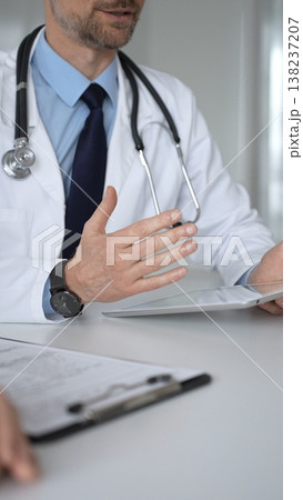 Doctor man interacting with patient during consultation, using digital tablet for modern medical healthcare technology. Medicine, healthcare and science concept Doctor man interacting with patient during consultation, using digital tablet for modern medical healthcare technology. Medicine, healthcare and science concept 138237207