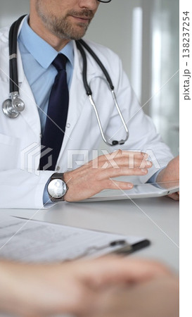 Doctor man interacting with patient during consultation, using digital tablet for modern medical healthcare technology. Medicine, healthcare and science concept Doctor man interacting with patient during consultation, using digital tablet for modern medical healthcare technology. Medicine, healthcare and science concept 138237254