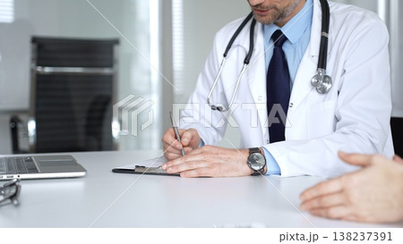 Doctor discussing medical information and treatment plans with a patient during a healthcare consultation in a clinic office. Medicine, healthcare and science concept 138237391