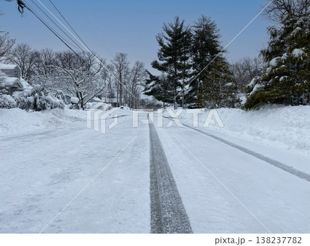 雪に覆われた住宅街の道路と一直線に伸びるタイヤ跡 雪に覆われた住宅街の道路と一直線に伸びるタイヤ跡 138237782