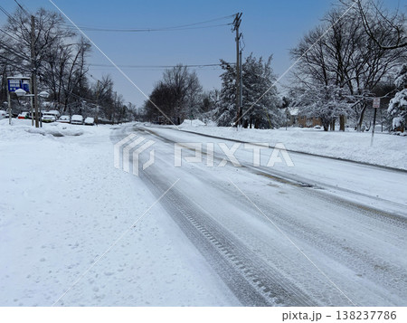 雪が積もった住宅街のカーブ道路とタイヤ跡が残る冬の風景 雪が積もった住宅街のカーブ道路とタイヤ跡が残る冬の風景 138237786