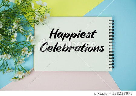 Happiest Celebrations text written on notepad with flowers decorations flat lay on multicolor pastel background 138237973