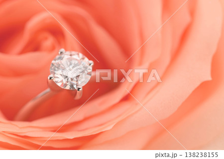 Diamond ring sits delicately on a coral rose 138238155