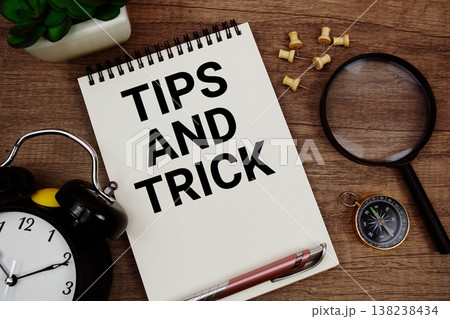 Tips and Trick text written on notepad with alarm clock, compass and magnifying glass flat lay on wooden background 138238434