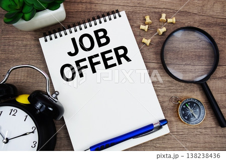 Job Offer text written on notepad with alarm clock, compass and magnifying glass flat lay on wooden background 138238436