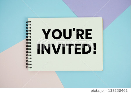 You're Invited! text written on notepad flat lay on multicolor pastel background 138238461