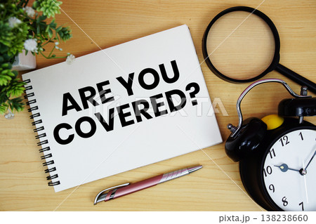 Are You Covered? text written on notepad with alarm clock and magnifying glass flat lay on wooden background 138238660