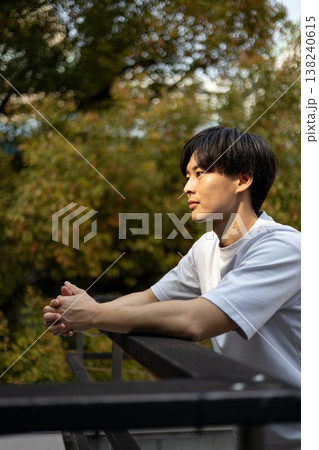 屋外で考え事をしている一人の若い男性 屋外で考え事をしている一人の若い男性 138240615