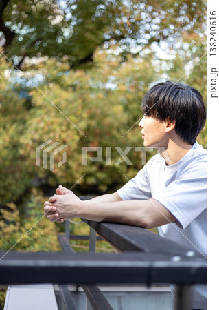 屋外で考え事をしている一人の若い男性 138240616