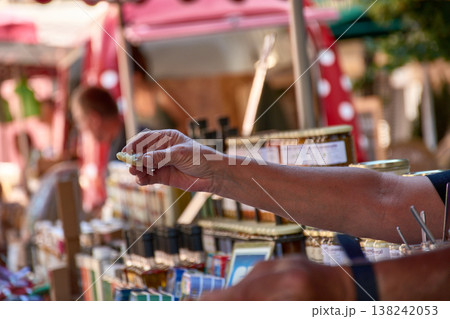 A customer's hands accepting a tasting at a lively market stall in Aix-en-Provence, France. A customer's hands accepting a tasting at a lively market stall in Aix-en-Provence, France. 138242053