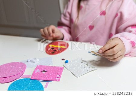 Child hands making festive easter egg craft with glue and foam shapes. Child hands making festive easter egg craft with glue and foam shapes. 138242238