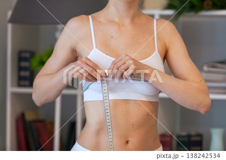 young adult woman measuring her chest at home 138242534