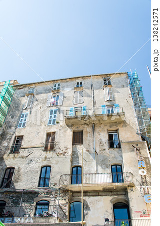 明るい日差しの下の遮光扉の付いたパステルカラーの建物　地中海に浮かぶフランス領のコルシカ島にて 138242571
