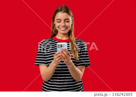 Pretty Woman Surfing Internet On Smartphone. Girl With Smile On Red Background. 138242805