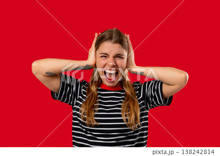 Woman reacts with frustration by blocking out noise or unwanted information. Stress, overload, conflict, workplace disagreement, rejection of opinions in business context. Woman reacts with frustration by blocking out noise or unwanted information. Stress, overload, conflict, workplace disagreement, rejection of opinions in business context. 138242814
