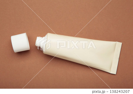 Beige tube of cream on brown background. Mockup plastic tube for cosmetics 138243207