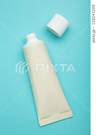Beige tube of cream on blue background. Mockup plastic tube for cosmetics. Vertical photo Beige tube of cream on blue background. Mockup plastic tube for cosmetics. Vertical photo 138243208