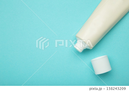 Beige tube of cream on blue background. Mockup plastic tube for cosmetics. Space for text Beige tube of cream on blue background. Mockup plastic tube for cosmetics. Space for text 138243209