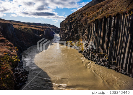 Discover the unique landscapes of Studlagil Canyon in Iceland, featuring striking basalt columns and a clear turquoise river flowing through dramatic rock formations. 138243440