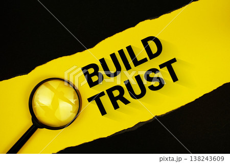 Build Trust text on yellow with black paper torn ripped and magnifying glass 138243609