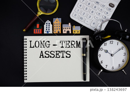 Notepad with the phrase "Long - Term Assets" surrounded by a pen, calculator, magnifying glass, clock, and house model Notepad with the phrase "Long - Term Assets" surrounded by a pen, calculator, magnifying glass, clock, and house model 138243697