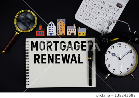 Notepad with the phrase "Mortgage Renewal" surrounded by a pen, calculator, magnifying glass, clock, and house model 138243698