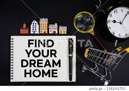 Notepad with the phrase "Find Your Dream Home" surrounded by a pen, mini trolley shopping cart, magnifying glass, clock, and house model 138243701