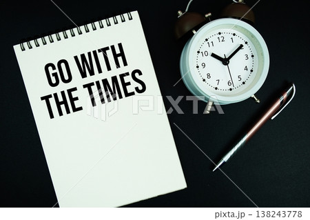 Go With The Times text written on notepad with pen and alarm clock Go With The Times text written on notepad with pen and alarm clock 138243778