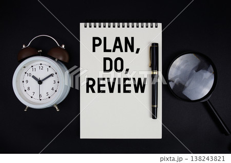 Plan, Do, Review text written on notepad with alarm clock top view on black background Plan, Do, Review text written on notepad with alarm clock top view on black background 138243821