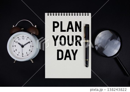 Plan Your Day text written on notepad with alarm clock top view on black background 138243822