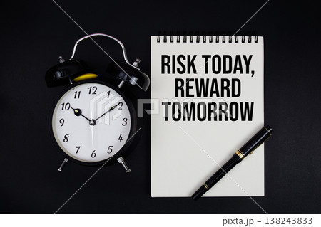 Risk Today, Reward Tomorrow text written on notepad with alarm clock top view on black background Risk Today, Reward Tomorrow text written on notepad with alarm clock top view on black background 138243833
