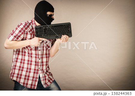 Man wearing balaclava holding keyboard Man wearing balaclava holding keyboard 138244363